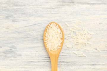 Long Basmati rice in wooden spoon and bunch on white background, copy space. Macro. Flat lay. Diet and weight loss concept