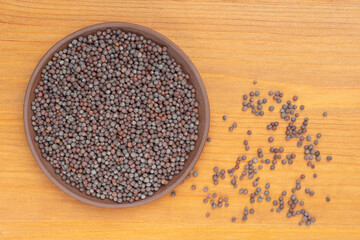 Mustard in clay plate and scattered in a heap on yellow wooden background. Healthy diet concept