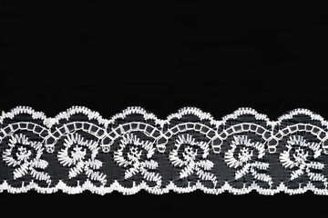 White lace on black background isolated horizontally. Sewing concept