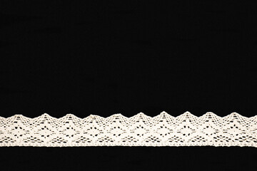 White lace in shape of ribbon on black background isolated. Sewing concept - obrazy, fototapety, plakaty