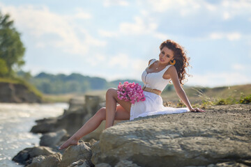 Fototapeta na wymiar Beautiful woman in white dress on the bank of a river in summer.