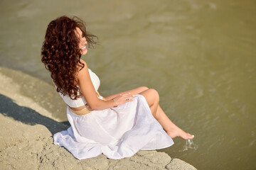 Fototapeta na wymiar Beautiful woman in white dress on the bank of a river in summer.