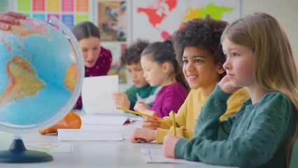 Group of multi-cultural students with teachers in classroom looking at globe in geography lesson - shot in slow motion