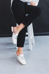 White female leather slippers close-up on female legs. New collection of women's summer leather shoes.