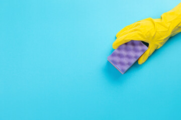 worker's hand in a yellow rubber protective glove with a purple sponge or dishwashing. A maid or housewife takes care of the house. general or regular cleaning. 