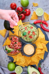 freshly made salsa and guacamole dip sauce with nacho chips on stone serving board