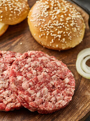 The raw ingredients for the homemade burger. Burger patties. Raw mince meat cutlet, ground beef and pork with bun. Grey background.