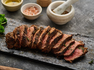 Grilled sliced beef steak on cutting board over grey table. Beef tenderloin steak. Filet Mignon...