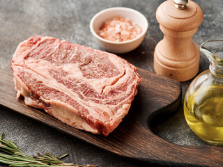 Raw ribeye steak on a wooden board. Preparing raw beef steak for barbecue grill.
