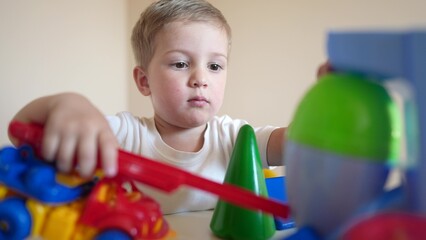 baby boy a playing with toy car and cubes. happy family kid dream concept. lifestyle baby son blond plays with cubes a and fire truck car. child in kindergarten playing with toys
