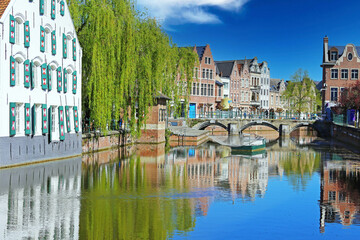Lier, Belgium - Romantic idyllic water town village moat, ancient medieval houses, green weeping willow tree, stone arch bridge, blue clear sky