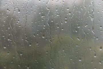 Raindrops drip down on the window glass. Soft selective focus.