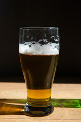 beer in a glass near a green bottle and on a black background