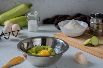 The process of making pancakes from zucchini. Bowl with zucchini puree, egg and salt.  Step-by-step photo recipe for making dough for zucchini fritters (pancakes).