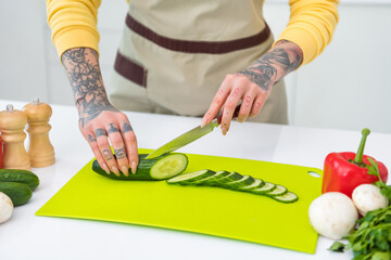 Cropped view portrait of attractive girl preparing fresh organic meal cutting vegs learning at home house kitchen indoors