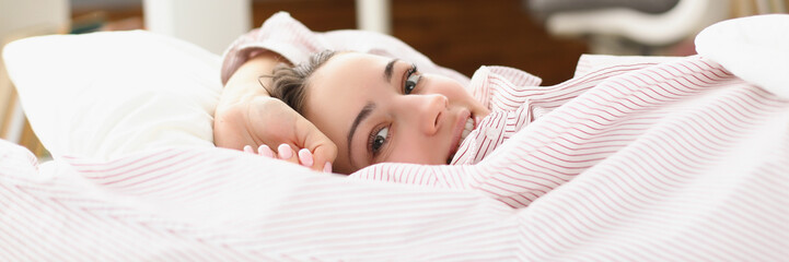 Obraz premium Happy young woman waking up in cozy home bed in good mood