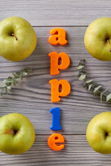 Apple word and green apples on grey table. Flat lay top view.