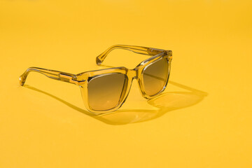 Fashion sunglasses in sunlight on summer pastel yellow background. Woman stylish eyeglasses for...