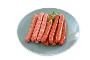 saucisses et merguez crues dans une assiette sur un fond blanc 