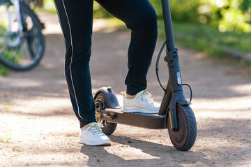 Young woman on an electric scooter on a dirt road in the park