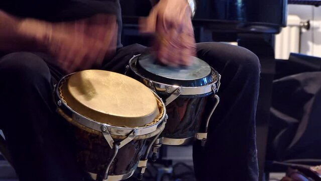 A man plays the bongo drums. 