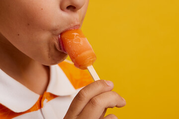 mouth close-up appetizing eating ice cream on a stick on a yellow background
