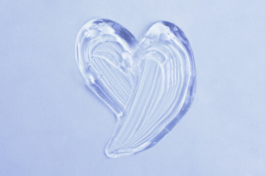 Cosmetic gel in shape of heart on the blue background.Copy space for text,mockup concept.
