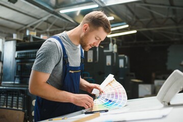 Portrait of production line worker controlling manufacturing process of modern packaging industrial...