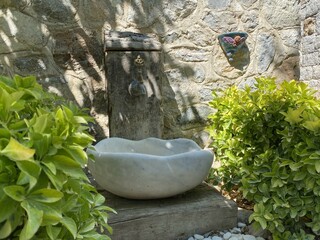 Antique fountain and marble sink in the garden, stone wall in the background, Turkish Ottoman style