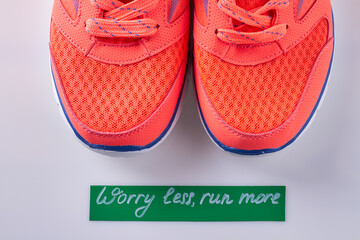 Close up pair of sport red shoes on white background. Worry less run more inscription.