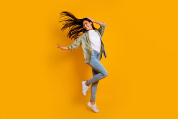 Full size portrait of overjoyed pretty person jumping flying hair isolated on yellow color background