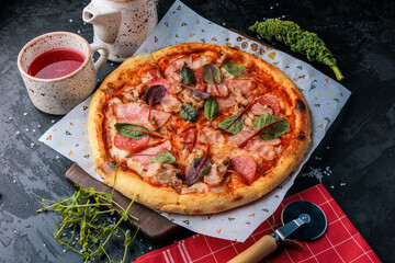 Traditional italian pizza with salami, cheese, tomatoes, mushrooms, greens. Top view at dark stone table. Italian food background.