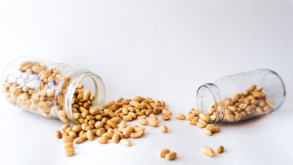 Roasted peanuts in jar isolated on white background. Groundnut seeds. Many lots of pieces of beer...