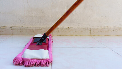 Someone using flat wet-mop pad to clean tiled home floor, close up and low view cropped image of...