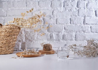 Cotton flower and wicker bag vase of plant style on the white table, brick wall background, still life, decoration.