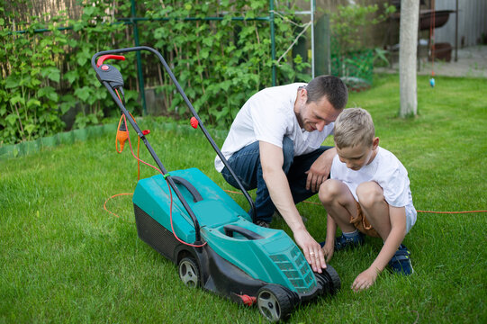 Dad And His Curious Son Mow The Lawn. Disassemble The Lawn Mower