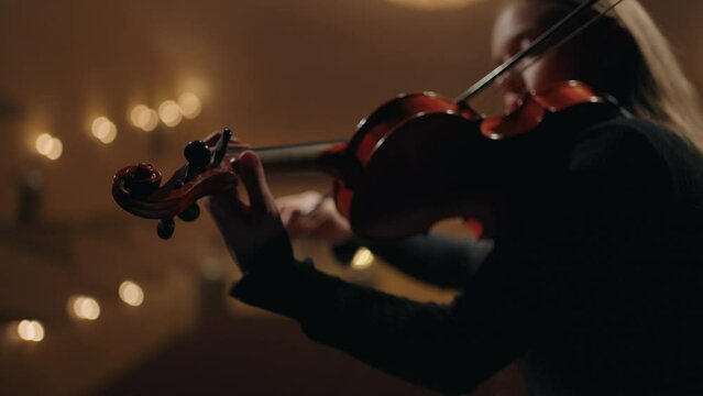 female violinist is playing violin in music school, closeup of fiddle in hands of woman