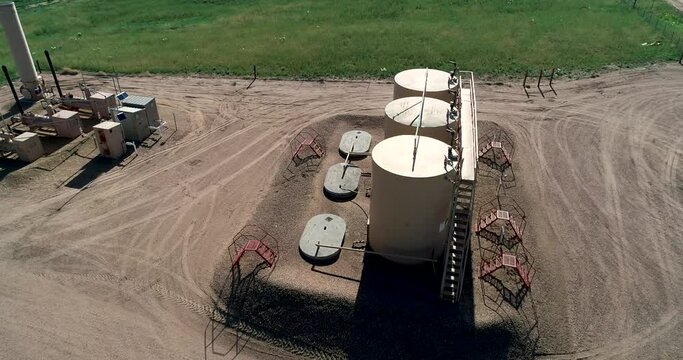 Fracking pad with three large petroleum tanks.  June 2022.