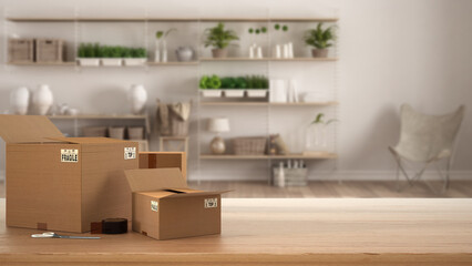 Wooden table, desk or shelf with stack of cardboard boxes over blurred view of living room with cozy shelving system, modern interior design, moving house concept with copy space