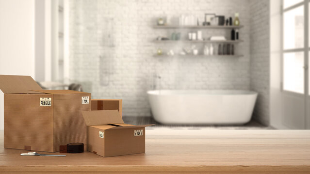 Wooden table, desk or shelf with stack of cardboard boxes over blurred view of vintage bathroom with bathtub, modern interior design, moving house concept with copy space