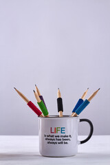 Vertical shot various colorful pencils in a cup. Life is what we make it, always has been, always will be. White background and copy space.