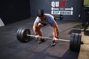 Young strong man doing deadlift exercise for bodybuilder's abdominal muscles in gym