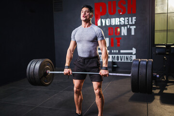 Fototapeta na wymiar Bodybuilder's abdominal muscles. Young strong man doing deadlift exercise in gym