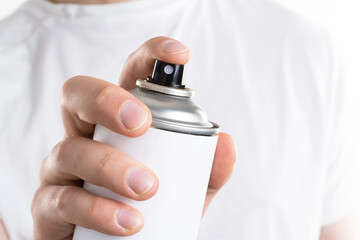 Man's hand holds a can of aerozols