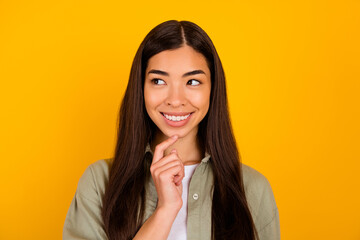 Portrait of minded cheerful girl finger touch chin look interested empty space isolated on yellow...