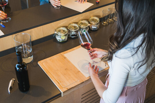 Crop female sommelier swirling wine in glass