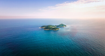 Green island in endless turquoise sea at sundown