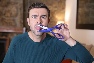 Angry man cutting tongue with scissors