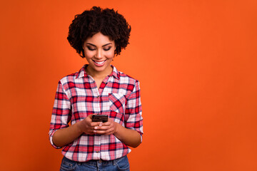 Photo of attractive positive lady use telephone typing post enjoy fast speed isolated on orange color background