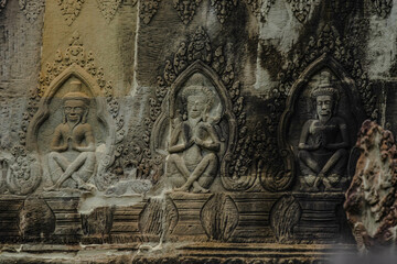 A sandstone wall carving depicting a hermit sitting with hands on her knees in Angkor Wat, Siem Reap, Cambodia.